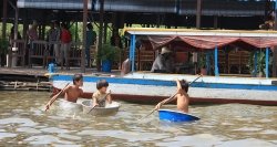 Les enfants sur les bacs plastiques au village flottant Chong Khneas